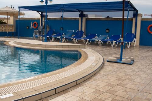 a swimming pool with chairs and a blue building at Fun for all the family! in Żebbieħ