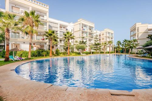 a large swimming pool in front of apartment buildings at Grand Appartement de standing sécurisé, proche plage avec piscine privée in Bouznika