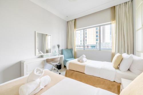 a bedroom with two beds and a desk and a window at Damac Mall Street Residences in Dubai