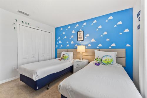 a bedroom with two beds and a blue wall with clouds at 8847 Candy Palm Rd in Kissimmee