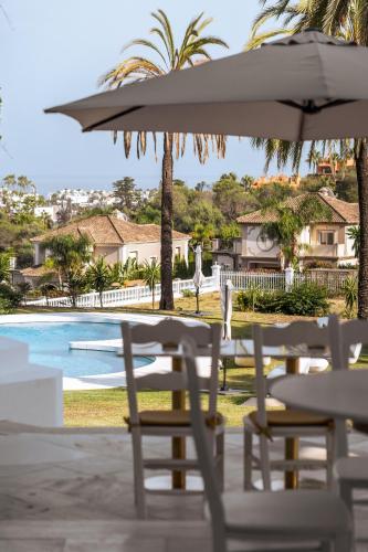 a table and chairs with an umbrella next to a pool at Palacio Suites Marbella in Marbella