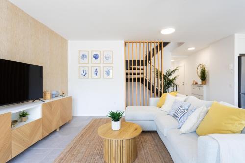 a living room with a white couch and a tv at Home2Book Panoramic Sunset Terrace Escape in Guía de Isora