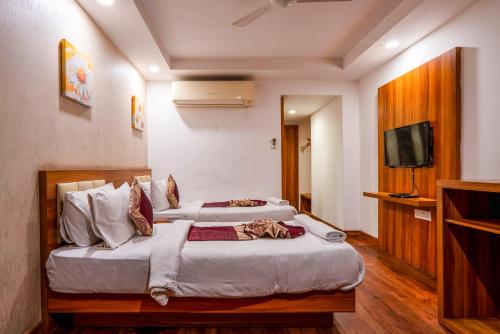 two beds in a hotel room with a television at Le Roi Jammu - Near Jammu Railway Station in Jammu