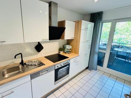 a kitchen with white cabinets and a sink and a window at Familiennest - Großzügige Familienwohnung mit Balkon in Zwenkau