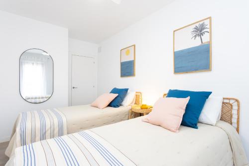 two beds in a room with white walls and a mirror at Home2Book Panoramic Sunset Terrace Escape in Guía de Isora