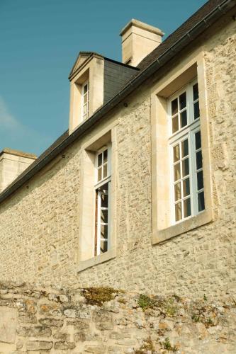two windows on the side of a stone building at Hôtel Le Manoir De Mathan Crépon à la campagne 5 mn d'Arromanches et 10 mn de Bayeux in Crépon