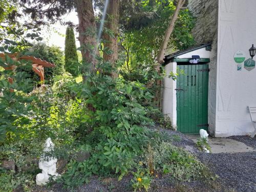 a building with a green door next to a tree at Beautiful and Authentic Cottage in Houffalize