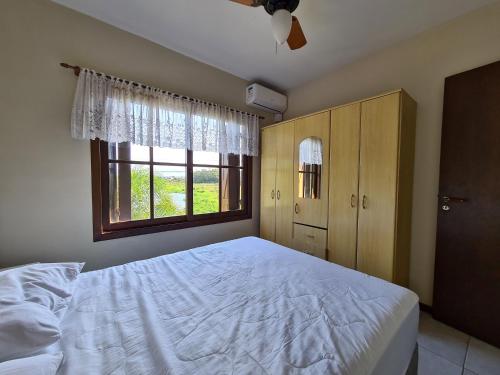 una camera da letto con un letto bianco e una finestra di Casa perto da praia - Frente para Lagoa a Garopaba