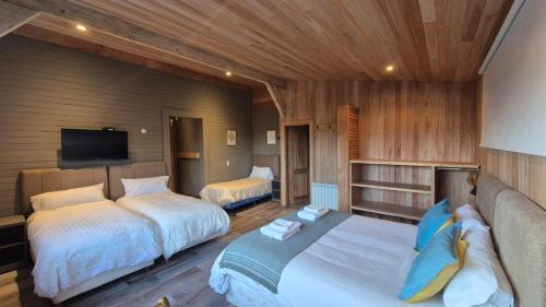 a bedroom with two beds and a flat screen tv at Hostería Las Cumbres in Villa La Angostura
