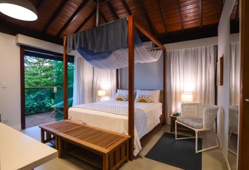 a bedroom with a canopy bed and a chair at Tesouro de Noronha in Fernando de Noronha