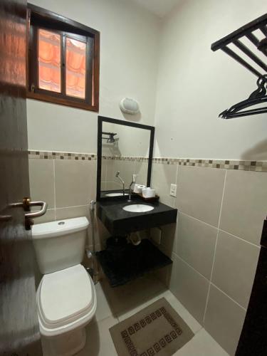a bathroom with a toilet and a sink and a mirror at Vila Verissimo in Jericoacoara