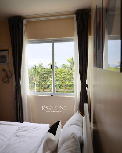 a bedroom with a window and a bed with white sheets at RYS & Shine in Silang