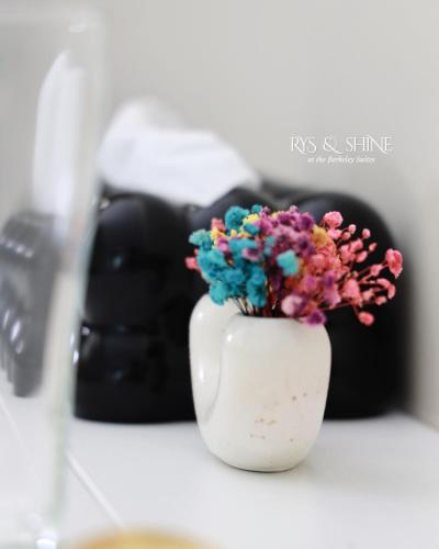 a white vase filled with colorful flowers on a counter at RYS & Shine in Silang