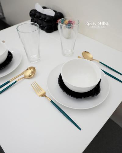 a table with a white plate and gold forks and spoons at RYS & Shine in Silang