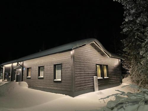 a building with lights on in the snow at night at Serenity Levi - Hot Tub & Sauna in Levi