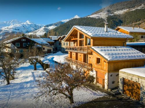 Una casa de madera en la nieve con montañas al fondo. en Les Moulins D'Angelina - OVO Network, en Séez