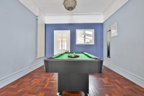 a pool table in a room with a blue wall at Elegant Victorian Home with Pool Table & Parking in Cardiff