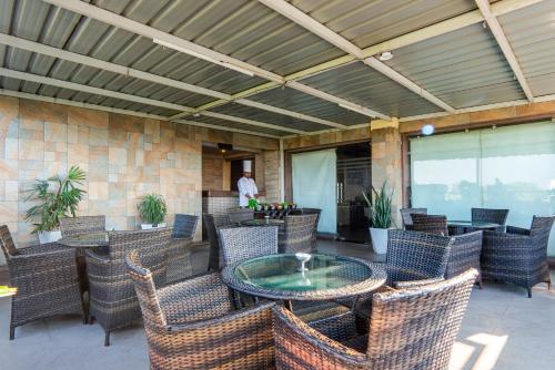 a patio with wicker chairs and a glass table at Le Roi Jammu - Near Jammu Railway Station in Jammu