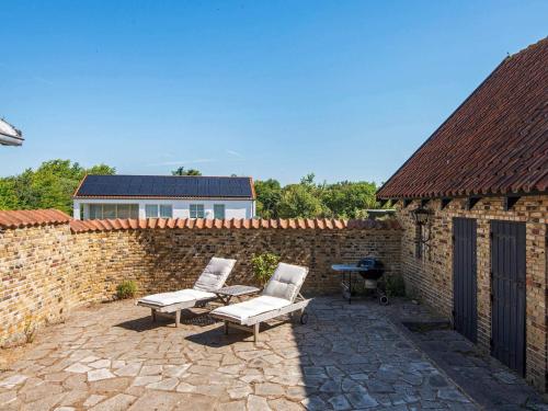 a patio with two chairs and a grill next to a brick wall at 5 person holiday home in Juelsminde in Juelsminde
