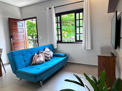 a blue couch in a living room with windows at Apto Funcional próximo a Orla do Centro HS4 in Ubatuba