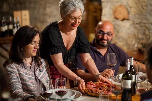 a woman standing at a table with a plate of food at Querceto Di Castellina in Castellina in Chianti