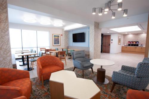 a waiting room with chairs and tables and a tv at Hampton Inn Salt Lake City-North in Woods Cross