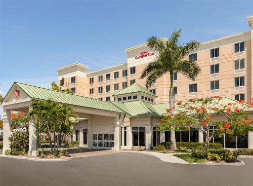 an exterior view of a hotel with a palm tree at Hilton Garden Inn Fort Myers Airport/FGCU in Fort Myers