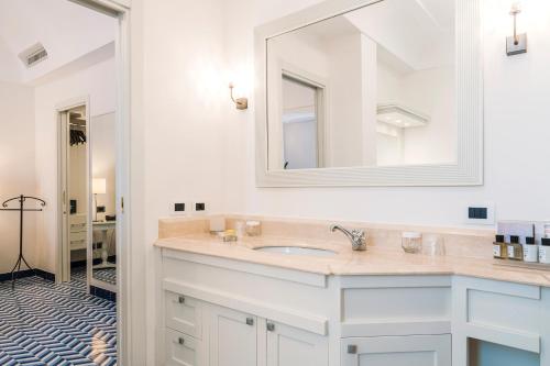 a white bathroom with a sink and a mirror at San Montano Resort & Spa in Ischia