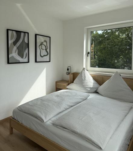 a white bedroom with a large bed and a window at Apartmenthaus Gilden 1 in Borken