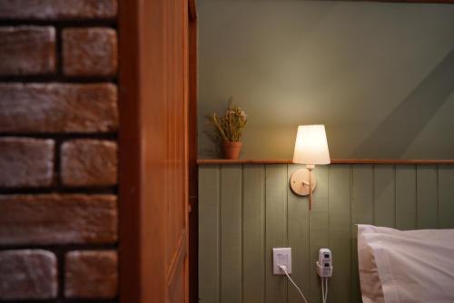 a lamp on a wall next to a bed at Pousada das Pedras in Monte Verde
