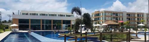 a resort with a swimming pool and a building at Porto de Galinha Muro Alto Flat in Ipojuca