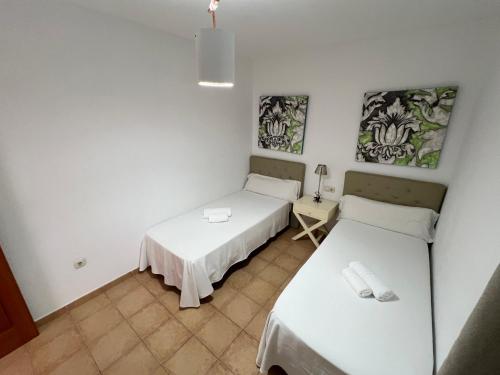 a room with two beds and a table at Anahi Home Corralejo - Villa Cardon 12 in La Oliva