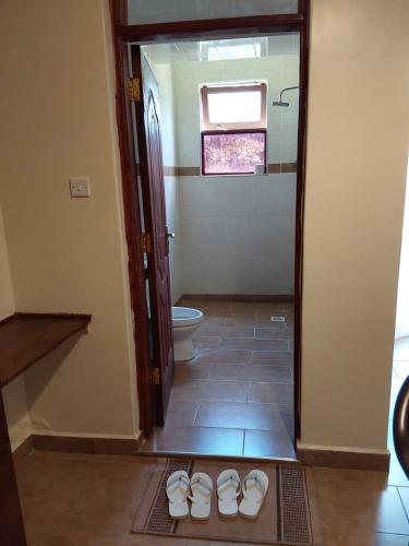 a bathroom with a toilet and a pair of shoes at Lantana Comfy in Kakamega