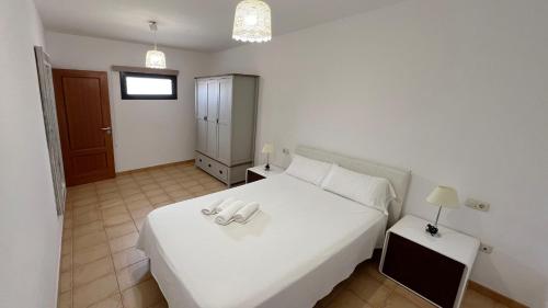 a white bedroom with a white bed and a night stand at Anahi Homes Corralejo- Dracaena 18 in La Oliva