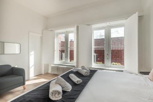 a white bedroom with a bed with towels on it at D28 Bruges in Bruges
