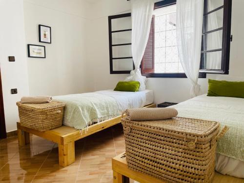 a bedroom with two beds and a bench and a window at Syrah Home in Tangier