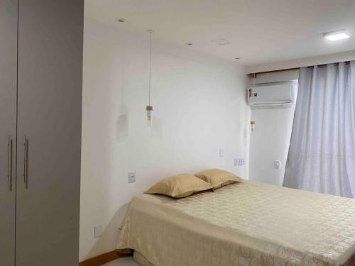 a small bedroom with a bed and a refrigerator at Garden - San Marino in Ilhéus