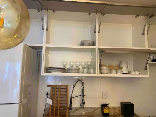 a kitchen with white cabinets with plates and dishes at Garden - San Marino in Ilhéus