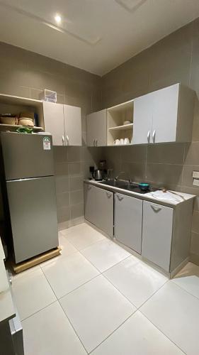 a kitchen with white cabinets and a refrigerator at Privée Cosy Moderne Equipée in Cotonou