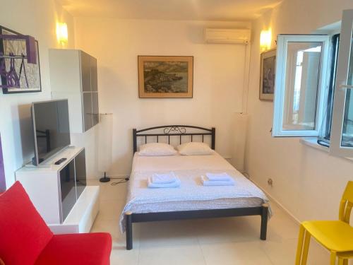 a small bedroom with a bed and a red chair at Apartment Sanja in Primošten