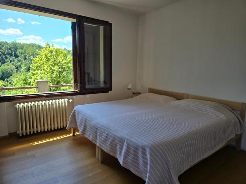 a bedroom with a bed and a large window at B&B Poggio di Vento sulla via degli Dei in Monzuno