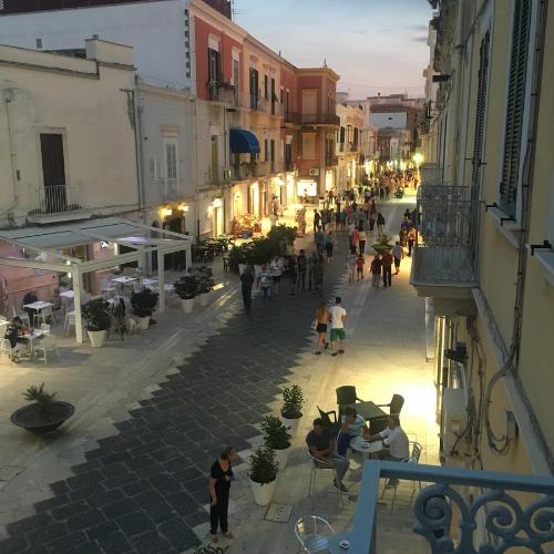 a group of people walking down a street at La Maison in Manfredonia