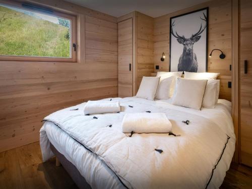a bedroom with a large white bed with a deer picture on the wall at Chalet Fanfoua - OVO Network in Combloux