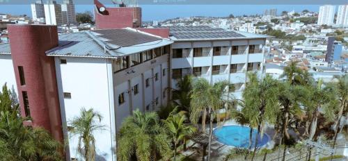 a building with palm trees in front of a city at Itatiba Orion Hotel in Itatiba