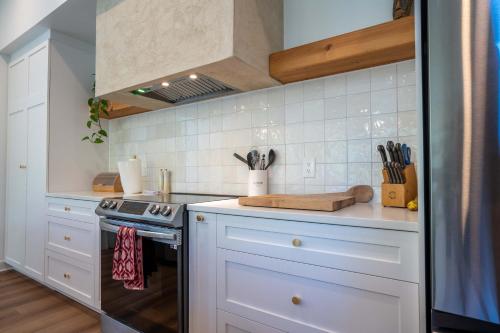 a kitchen with white cabinets and a stove top oven at Spa Pool table Lake access - Le 515 Beaulac in Chertsey