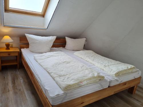 a large bed with white sheets and pillows at Reethäuser auf Rügen in Middelhagen