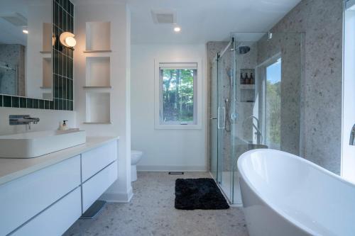 a white bathroom with a tub and a shower at Spa Pool table Lake access - Le 515 Beaulac in Chertsey