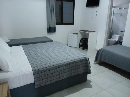 a hotel room with two beds and a sink at Pousada Parque Suites - Estacionamento e Piscina in Guarujá