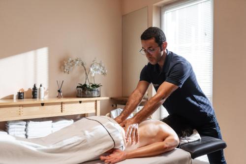 a man is cutting a mans back on a bed at Hotel Maximilian in Bad Griesbach