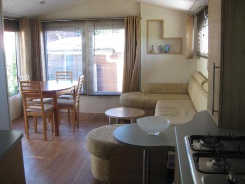 Saint-Nazaire-sur-CharenteにあるMobil Home 40 M², Proche De La Merのソファとテーブルのあるリビングルーム